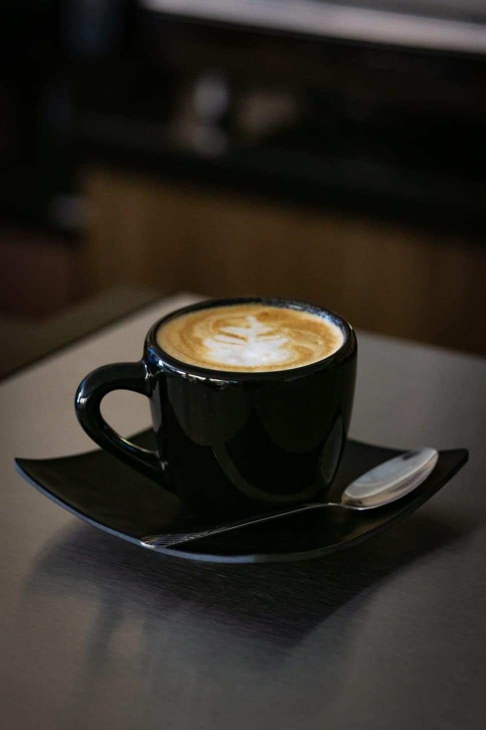 Cappuccino con arte latte en taza negra