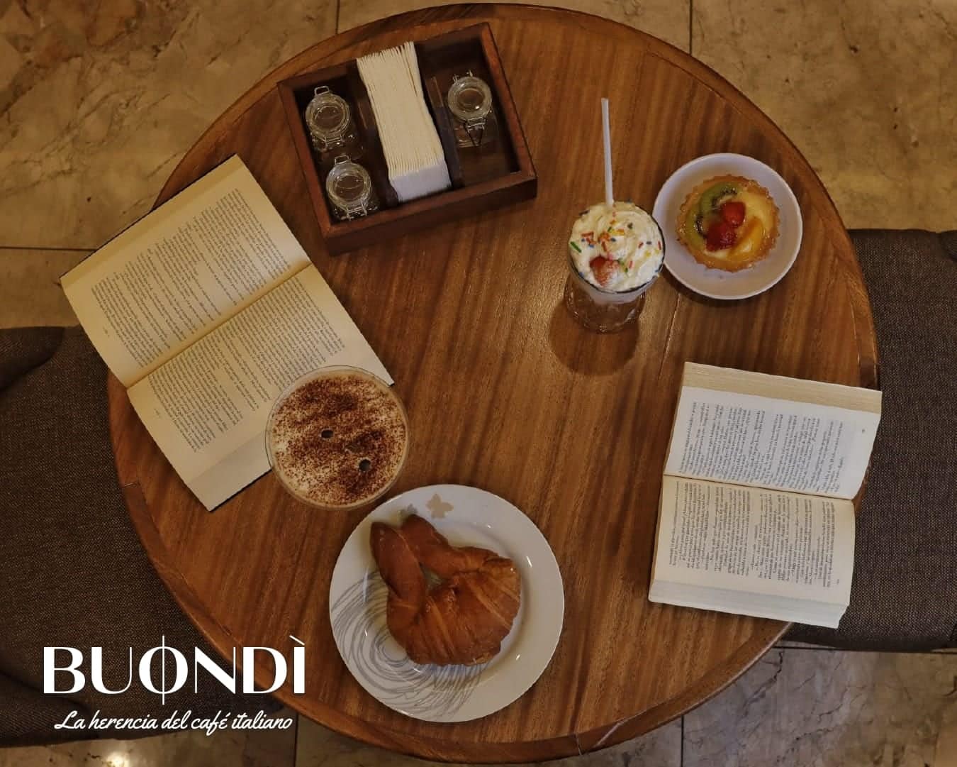 Mesa de Buondì vista desde arriba con libros, café y tarta de frutas
