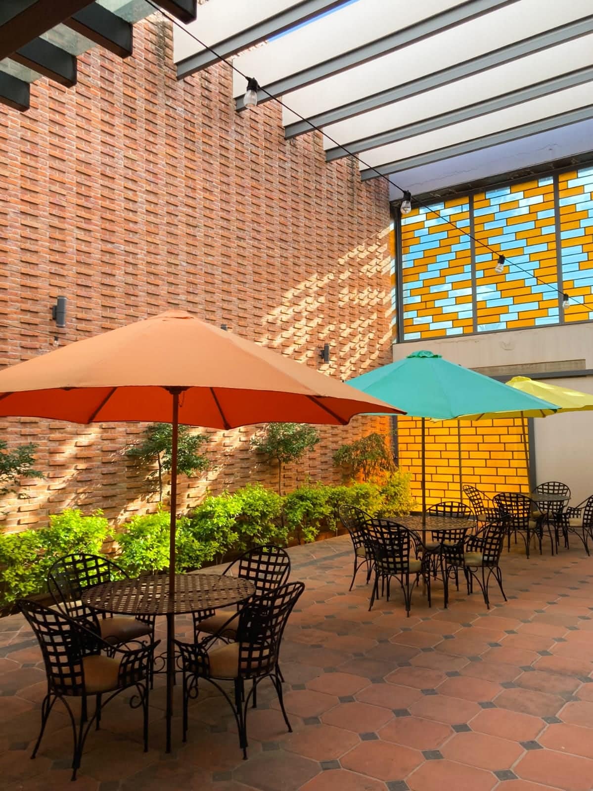 Terraza de Buondì con sombrillas de colores y muro de ladrillo